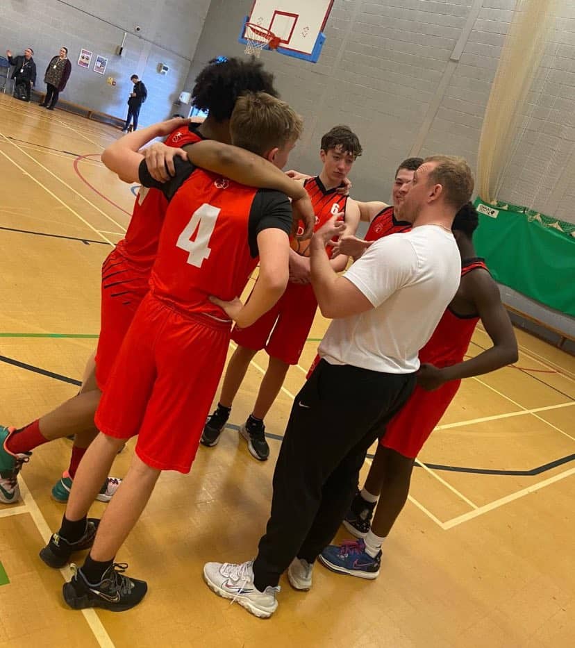 the Didsbury High School Under 16 basketball team huddle together on the court during their quarter fnal game in the Basketball England U16s competition.