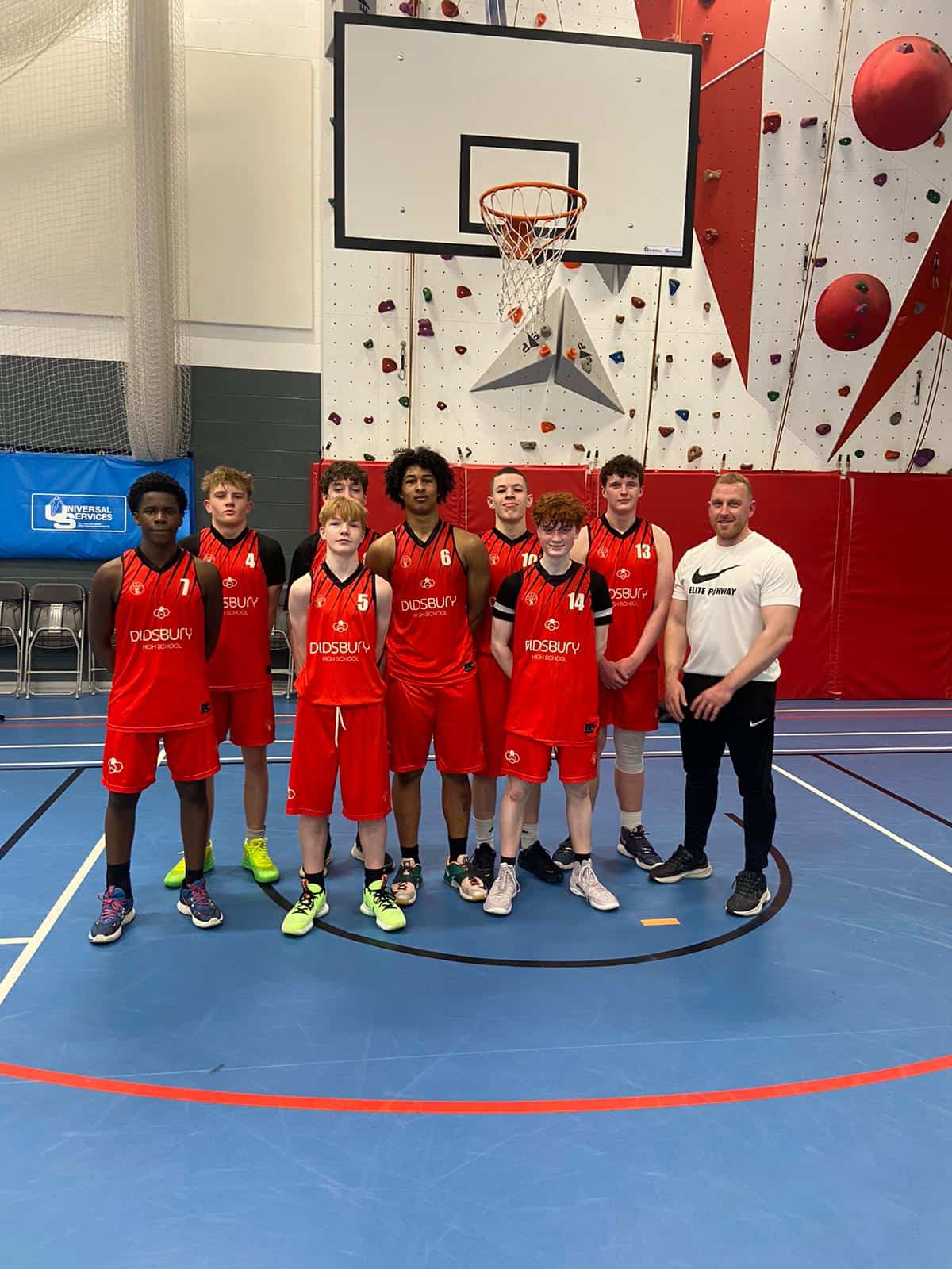 The Didsbury High School Under 16 basketball team stand together with their coach on the court after their semi final game in the Basketball England U16s competition.