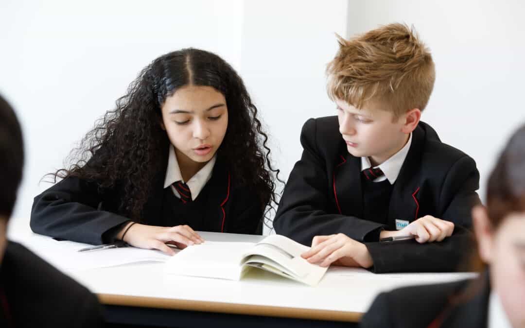 Image of two students at Didsbury High School reading from a textbook.
