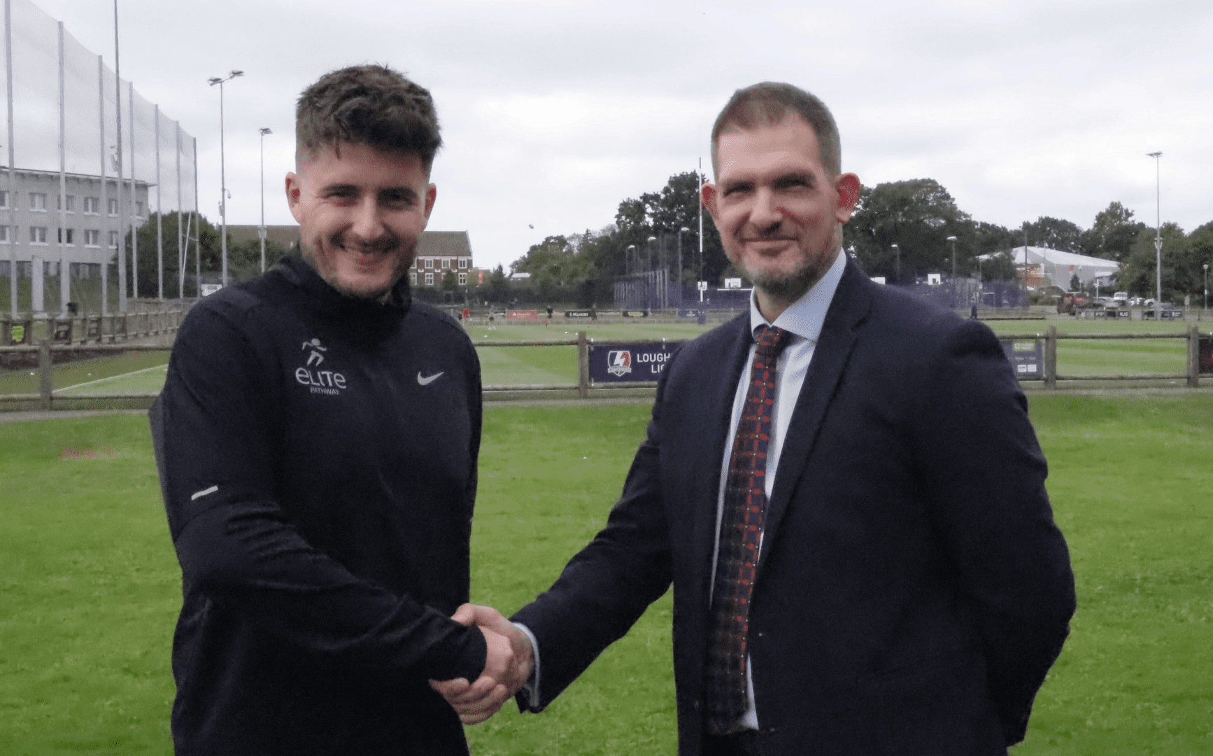 Two men shaking hands on sports field